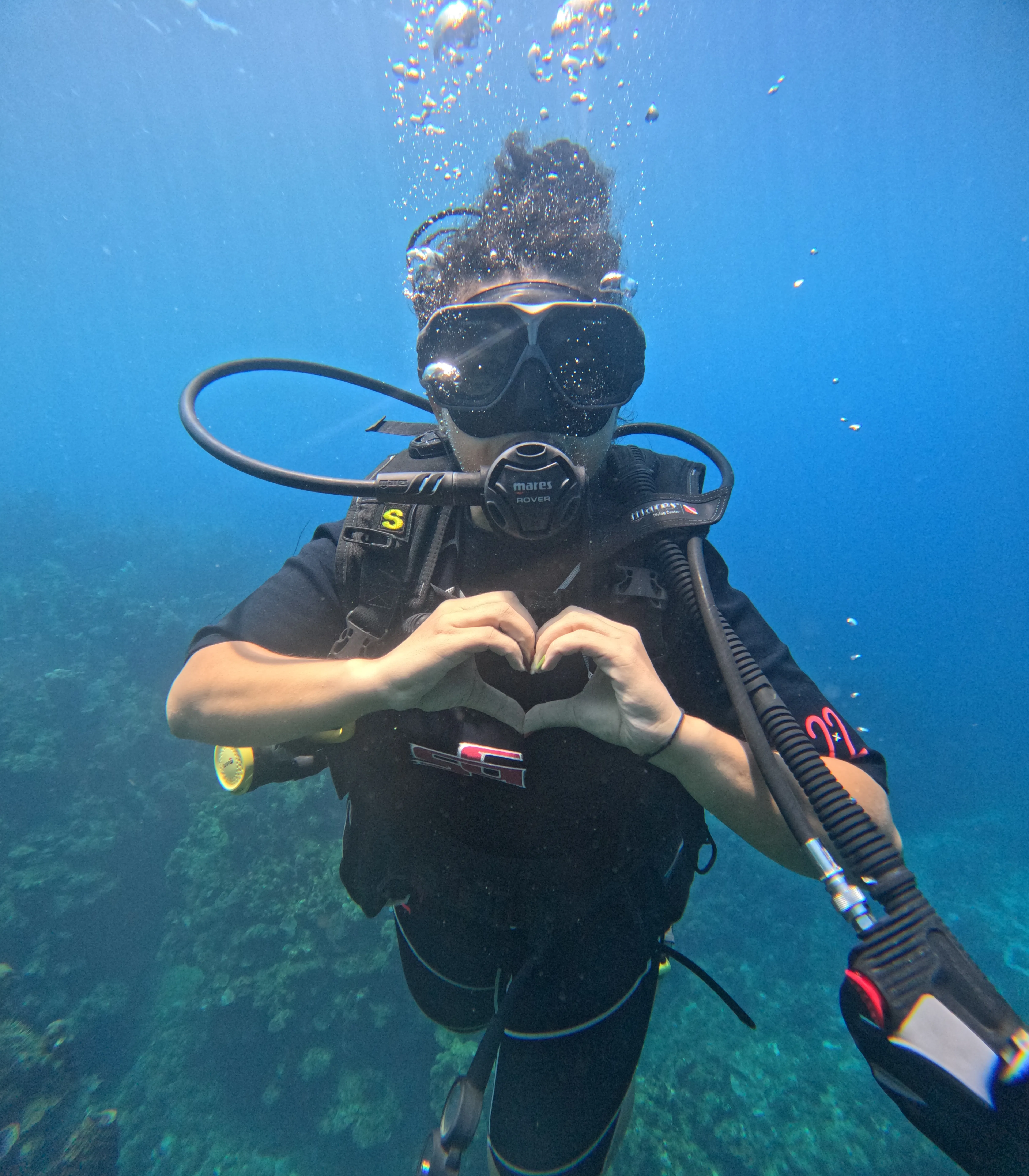 A scuba diver making a heart shape with their hands underwater